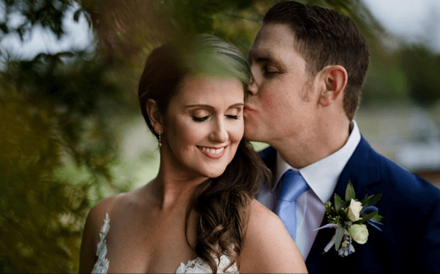 Groom kissing his smiling bride on the cheek