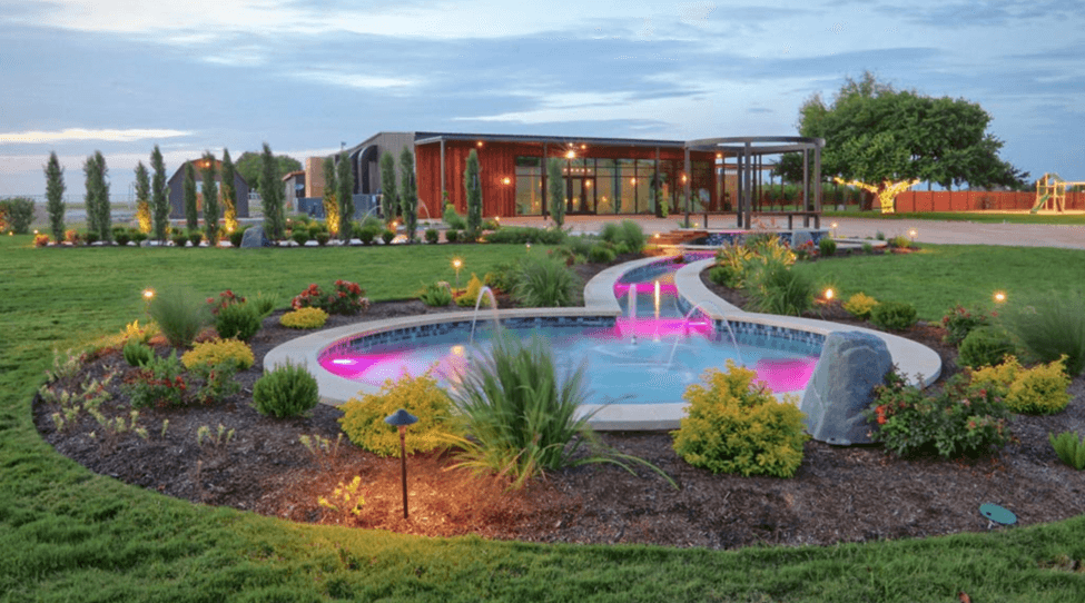 Modern event venue with a lit fountain garden at dusk