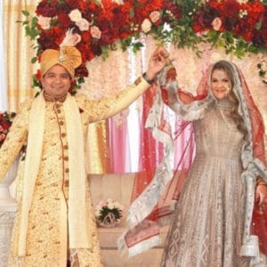 Mr. and Mrs. Ahmad dancing in front of a red rose backdrop