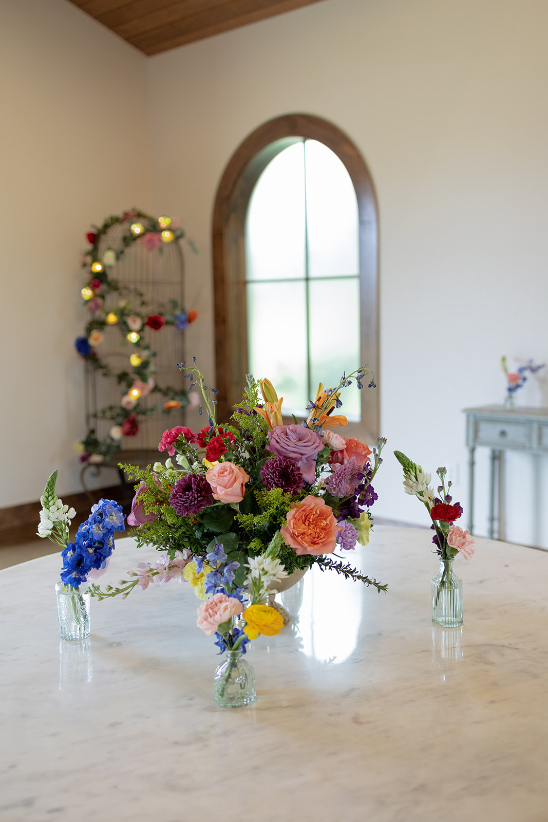 Bright mixed-flower centerpiece in a glass vase on a round table