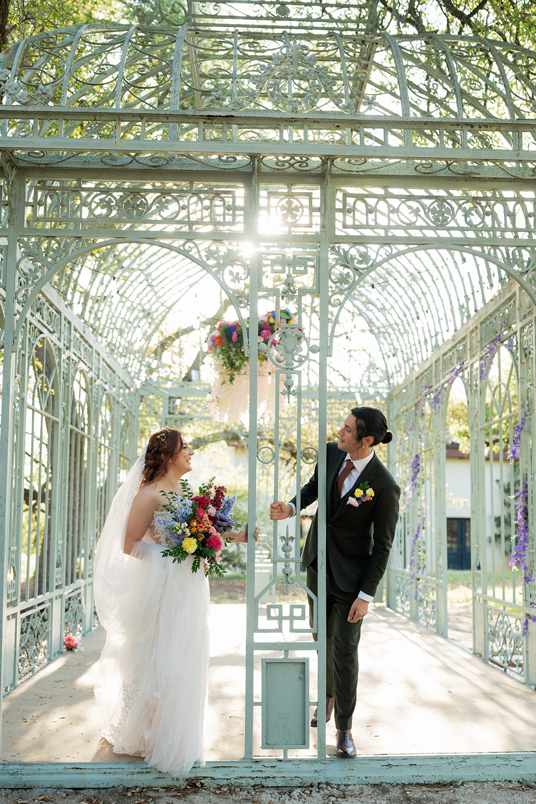 Bride and groom facing each other inside a glass conservatory