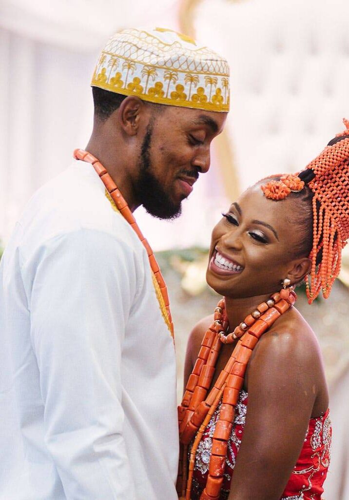benbree Bride and groom in coral beads and traditional wedding attire, smiling at each other