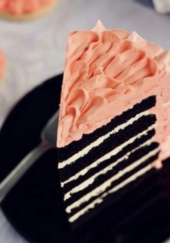Slice of layered chocolate cake with pink frosting